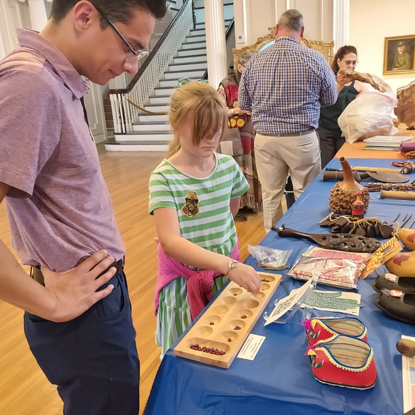 A Museum Volunteer teaching a kid how to play manacala, a game featured in the Sue Koenig's Window to the World: Mobile Museum